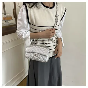 Detail of silver quilted handbag with metal twist lock and chain strap on a model