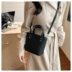 Detail of black lychee leather bucket bag with metallic studs and crossbody strap