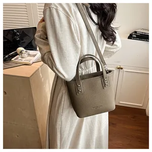 Detail of coffee grey bucket bag featuring lychee grain texture and metal hardware
