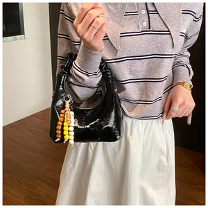 Detailansicht der schwarzen Lackleder-Cloud-Tasche mit Falten-Griff und bunten Perlen
