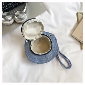 Dettaglio mini borsa a forma di cappello blu con cerniera e cinturino da polso