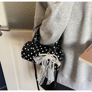 Detailed view of polka dot cylindrical handbag with pearl bow and lace ribbon accessory