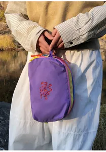 Macro detail of multi-layered colorful nylon zipper pouches and embroidery on purple fabric