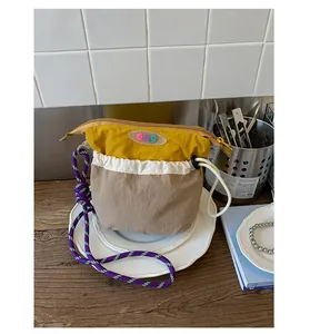 Detail view of colorful nylon crossbody bag with woven rope strap and front drawstring pocket