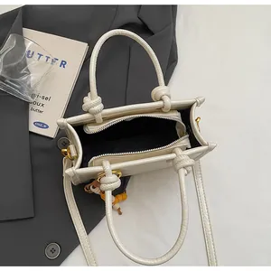 Top view of cream white crossbody bag showing internal zipper compartment and beaded charm