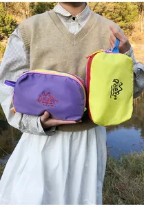 Detailed shot of purple and yellow nylon travel pouches with hand straps and mountain logo