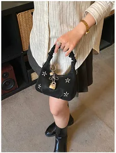 Detail of black embroidered flower handbag with heart lock charm and ruched handle