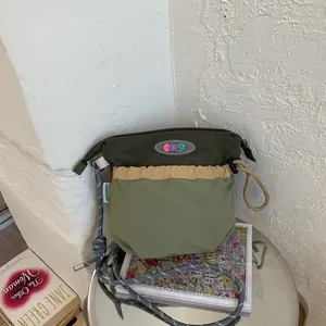 Modern color-block crossbody bag with adjustable drawstring strap on a silver surface