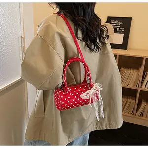 Close-up of red polka dot cylinder bag with lace pearl bow detail on mannequin