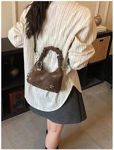 Detail of dark brown embroidered shoulder bag with floral patterns and a heart charm