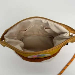 Cylindrical nylon crossbody bag in yellow and brown with a braided rope strap