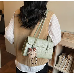Detail of light green shoulder bag with textured leather and cute plush bear charm