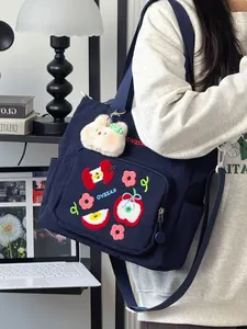 Détail du sac en toile bleu marine avec broderie pomme et charm ours en peluche