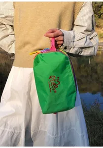 Detail of green nylon toiletry bag with vibrant multi-colored zippers and top handle