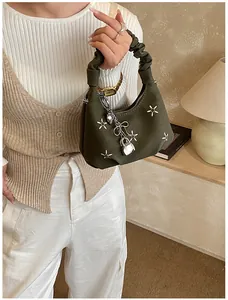Detail of olive green dumpling bag featuring silver floral sequins and a ruffled handle