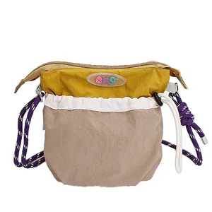 Three-color patchwork crossbody bag with drawstring and purple braided shoulder strap