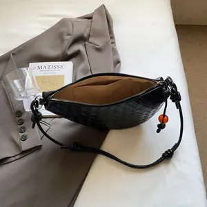 Detail view of black woven moon bag with amber bead charm and smooth leather texture