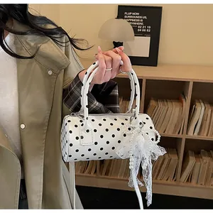 Close-up of polka dot barrel bag with pearl and lace bow charm detail on handles