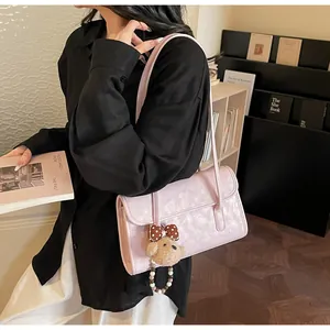 Detail of pink faux leather shoulder bag with cute brown polka dot bear charm accessory