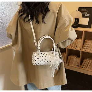 Detailed shot of a polka dot cylinder bag with a lace bow and pearl charm attachment