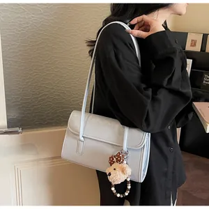 Detail of light blue faux leather shoulder bag featuring a cute plush bear charm accessory