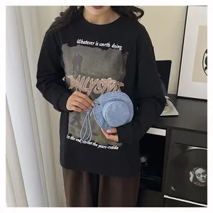 Primo piano di un mini portamonete a cappello in denim blu con portachiavi tenuto da una modella