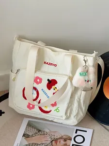 Détail du sac cabas en toile crème avec broderie rouge et écusson pomme mignon brodé