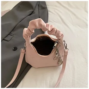 Pink crossbody dumpling bag with floral embroidery and ruched cloud handle on white fabric