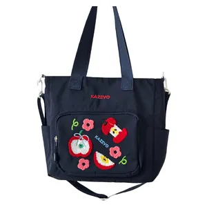Détail du sac cabas bleu marine avec broderie pomme et bandoulière réglable pratique
