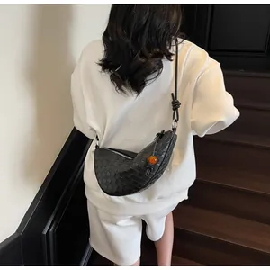 Detail of black woven leather crossbody bag with knot detail and amber bead decoration