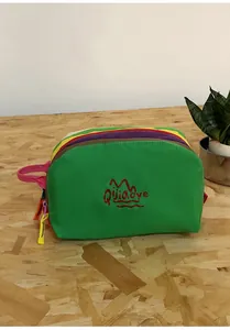 Detail of vibrant green nylon travel bag with multi-color layered interior and pink handle