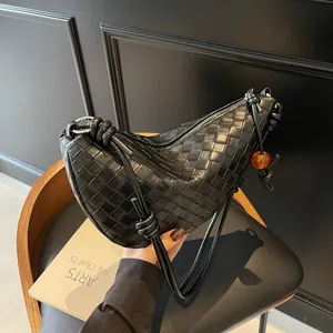 Minimalist black woven leather crescent shoulder bag with amber bead and long strap