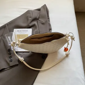 Chic cream woven crescent hobo bag on grey blazer background with soft lighting