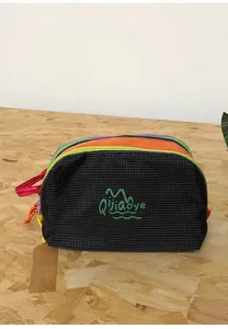 Close-up of a nylon travel toiletry bag featuring multi-layer colorful zippers and red handle