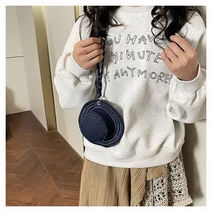 Dettaglio mini portamonete in denim blu a forma di cappello con cordino al collo