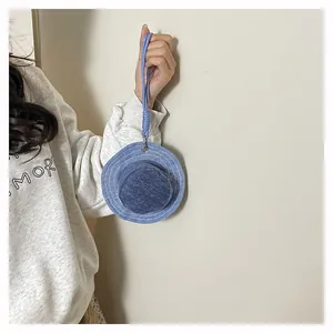 Dettaglio di un mini portamonete a forma di cappello alla pescatora in denim blu con laccetto