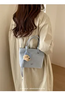 Détail du sac seau bleu clair avec poignée nouée et charmant ourson en peluche