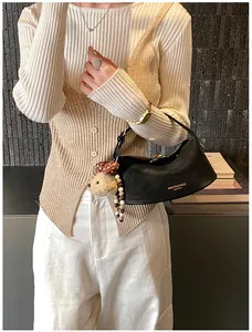 Détail du sac à main en cuir noir avec lettrage doré et charmant petit ours en peluche