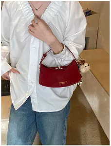 Détail du sac porté épaule en cuir rouge foncé avec lettrage doré et charme chien