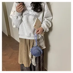 Mini accessorio portachiavi a forma di cappello blu mostrato su una modella in interni