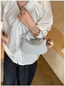 Détail du sac hobo bleu clair avec fermoir doré et pendentif d'ours en peluche
