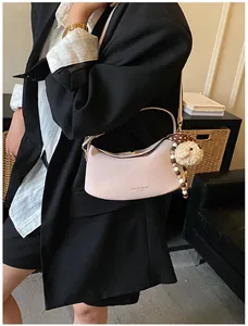 Détail du sac bandoulière demi-lune rose avec charme d'agneau et perles décoratives