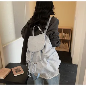 Détail d'un petit sac à dos bleu clair à motif étoiles avec cordon et fermeture éclair