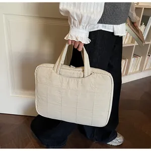Détail du sac d'ordinateur beige matelassé avec double poignées et fermeture éclair