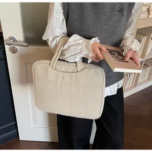 Sacoche beige matelassée pour ordinateur portable avec poignées dans un bureau