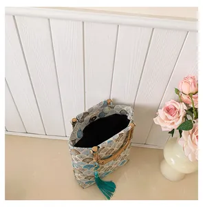 Detailed view of retro jacquard handbag with bamboo handle, wave pattern and tassel