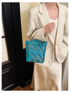 Detail of teal blue oriental jacquard bag with bamboo handle and elegant silk tassel