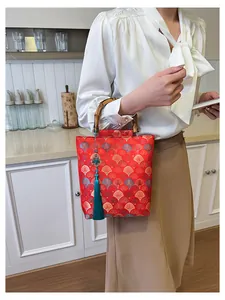 Detailed shot of red jacquard bag with bamboo handles and elegant cyan tassel pendant