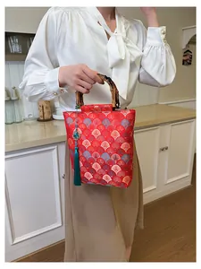 Detail of red brocade bag with bamboo handle and green tassel in a lifestyle setting