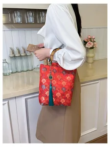 Detailed macro shot of red brocade fabric and bamboo handle with tassel on the handbag